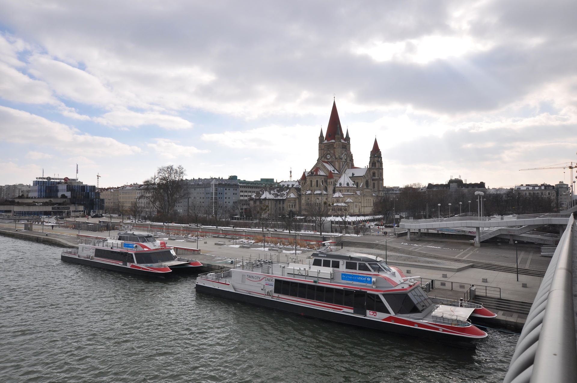 Neben der Reichsbrücke warten die TwincityLiner auf die nächste Fahrt nach Bratislava, dahinter die Franz-von-Assisi-Kirche